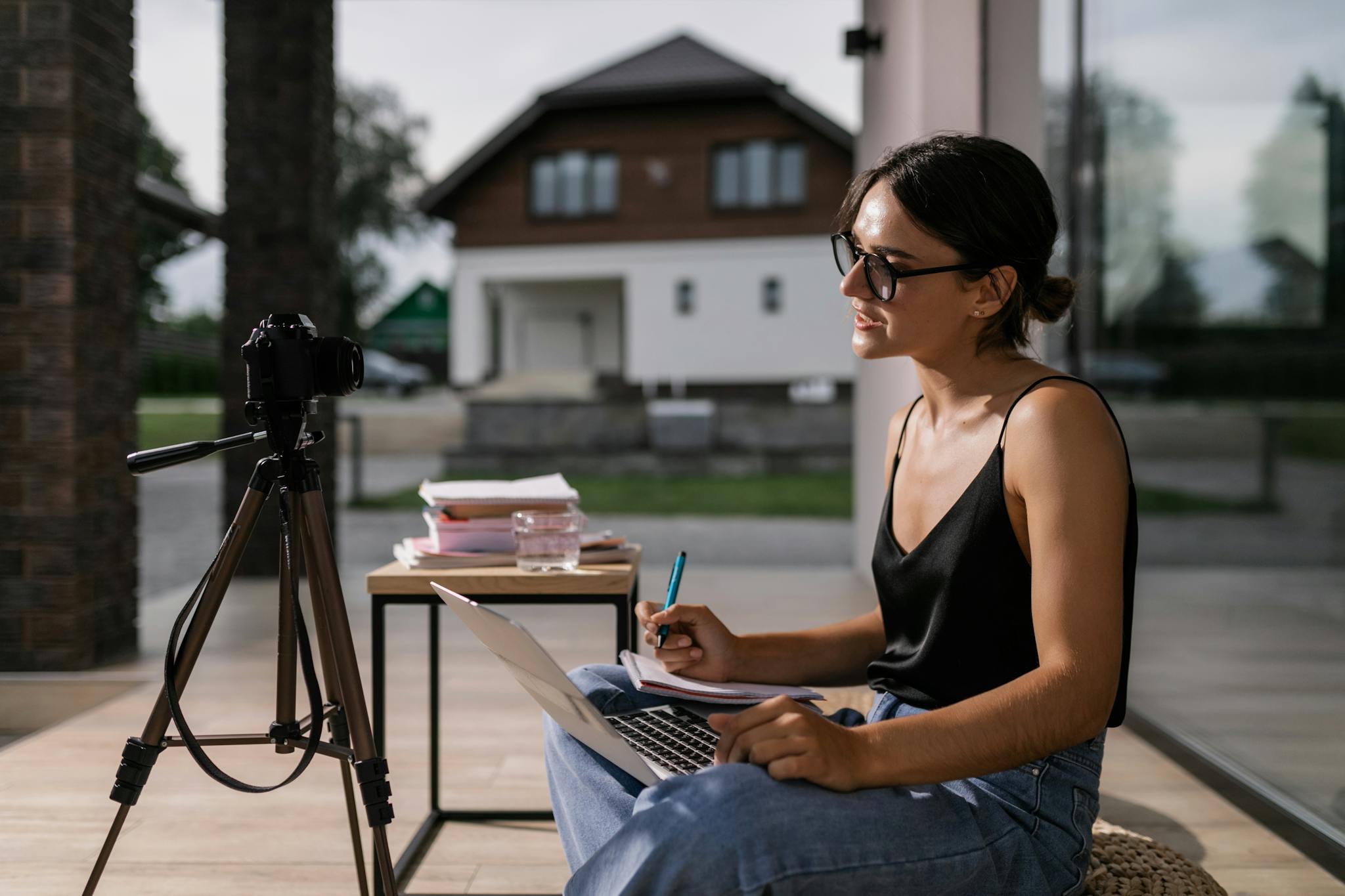 Woman sitting with laptop taking notes for an online class, intense focus outdoors.
